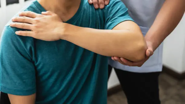 Physical therapist assisting patient's shoulder and elbow