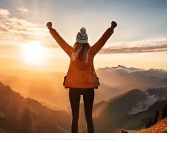 Hiker raising arms at sunrise mountain peak